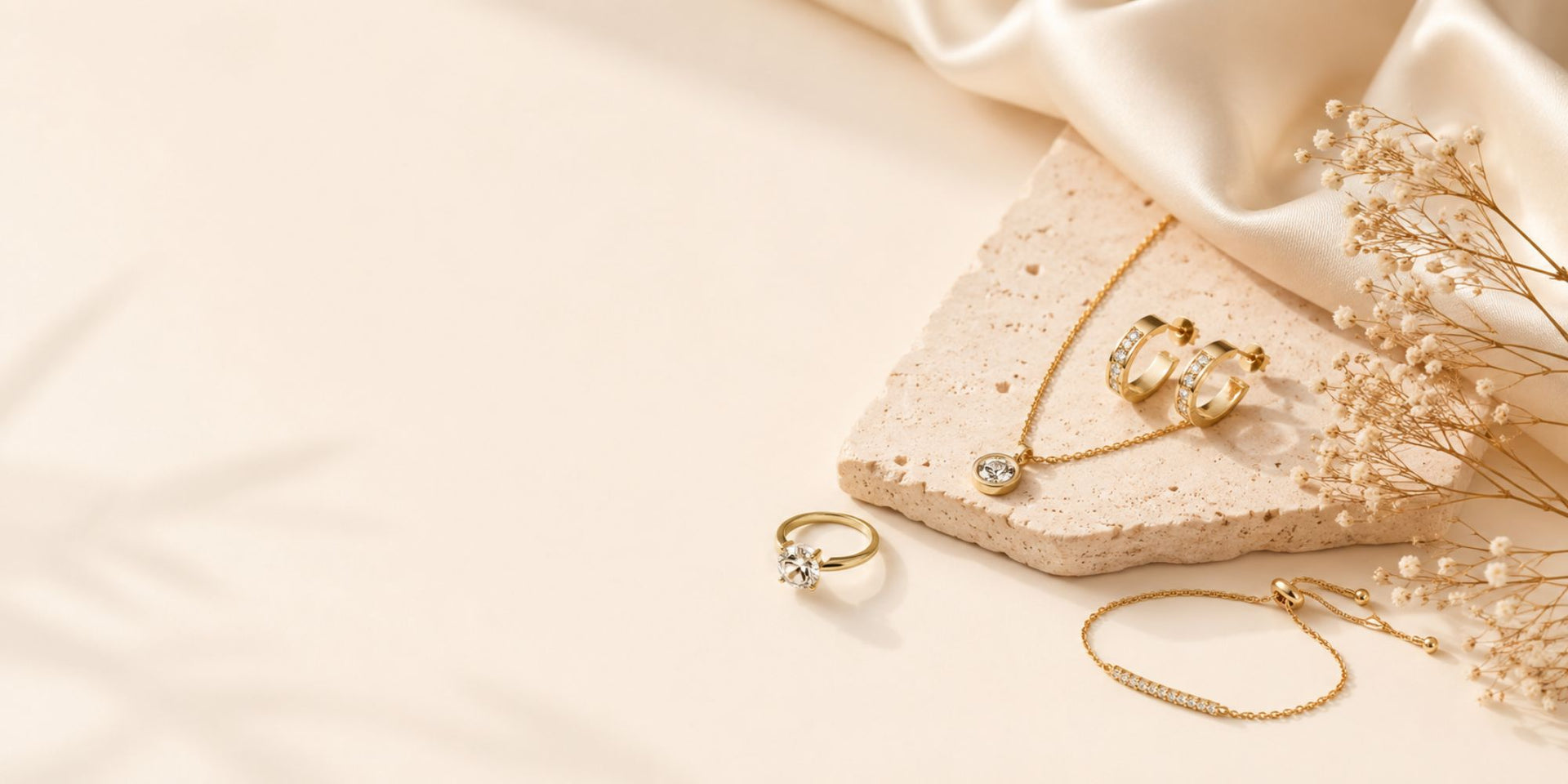 Gold jewelry including rings and a necklace on a soft beige fabric background